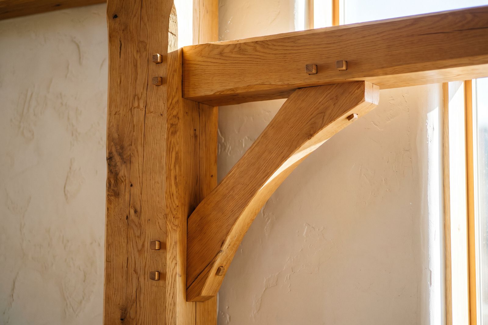 Pegged oak post and beam joint with a curved brace against a plaster wall