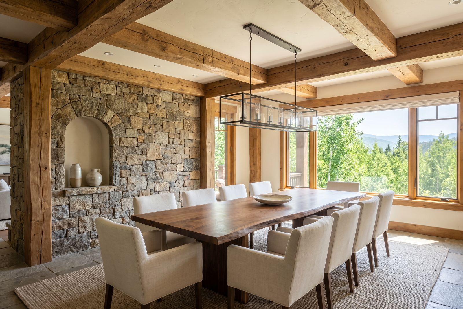 Dining room with a walnut table under timber beams beside an arched stone niche